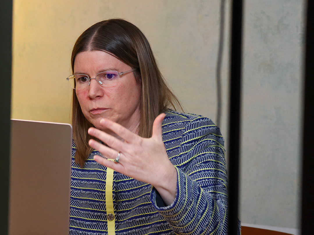 Sibylle Schwarz hinter einem Laptop während eines Webinars, mit den Händen interagierend